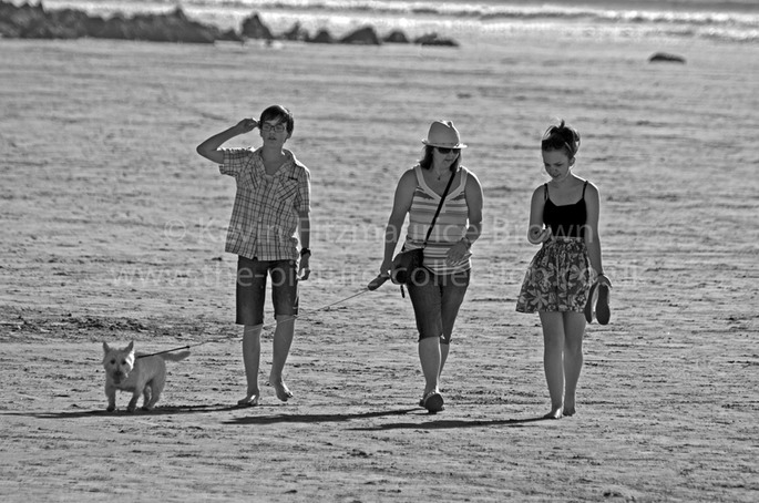 THREE YOUNG PEOPLE WALK A DOG ON  BROADHAVEN, PEMBROKESHIRE, WALES.
